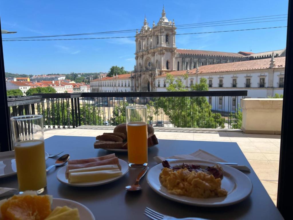 a table with a plate of food and orange juice at Hotel Santa Maria in Alcobaça