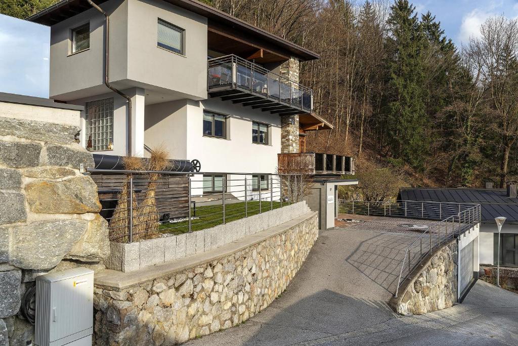 a house with a stone retaining wall and a fence at Bei Kompis in Jenbach