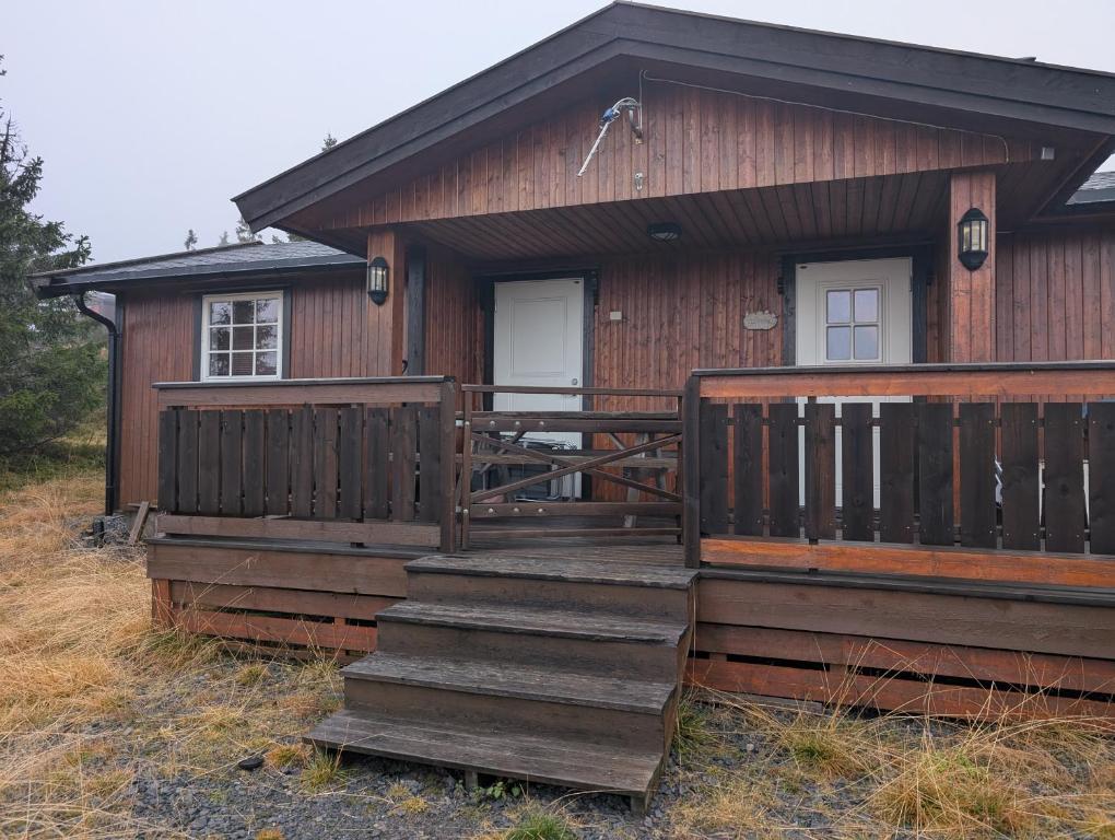 a wooden cabin with stairs leading to a porch at Feriehjemmet in Ringsaker