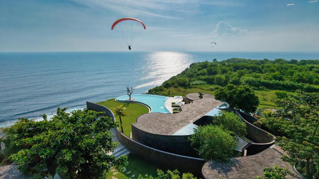 a paraglider is flying over the ocean at Nya Uluwatu in Uluwatu