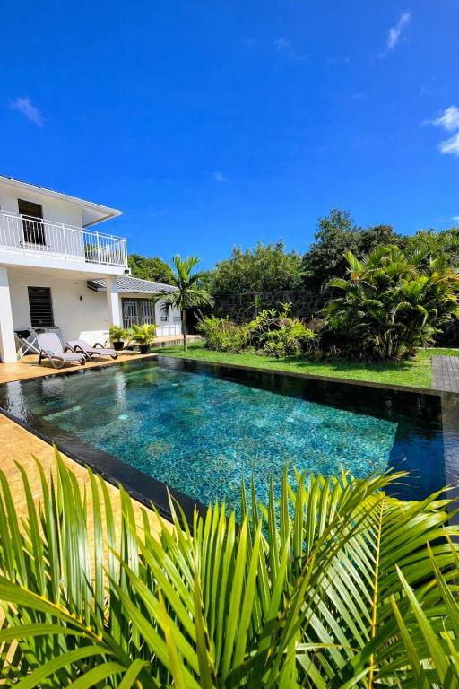 a swimming pool in front of a house at Vanilla Lodge Tropical Garden Suite with Outdoor Stone Bath & Bamboo Shower, inifinity pool in Cap Malheureux