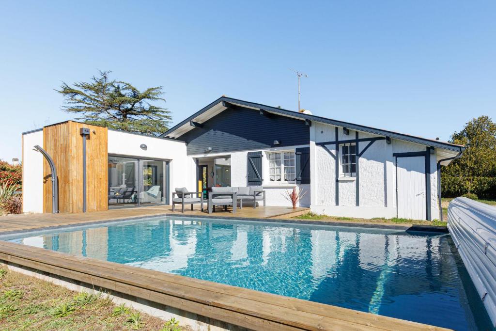 a swimming pool in front of a house at Villa Blue Pool - Welkeys in Seignosse