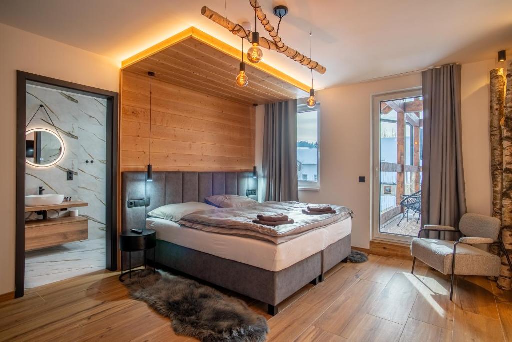 a bedroom with a large bed and a bathroom at RESORT JEZERNÍ Apartmány & Penzion Wellness in Železná Ruda