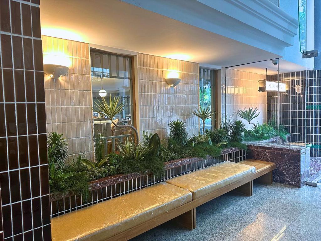 A long upholstered bench set into a plant-filled hotel entrance area.