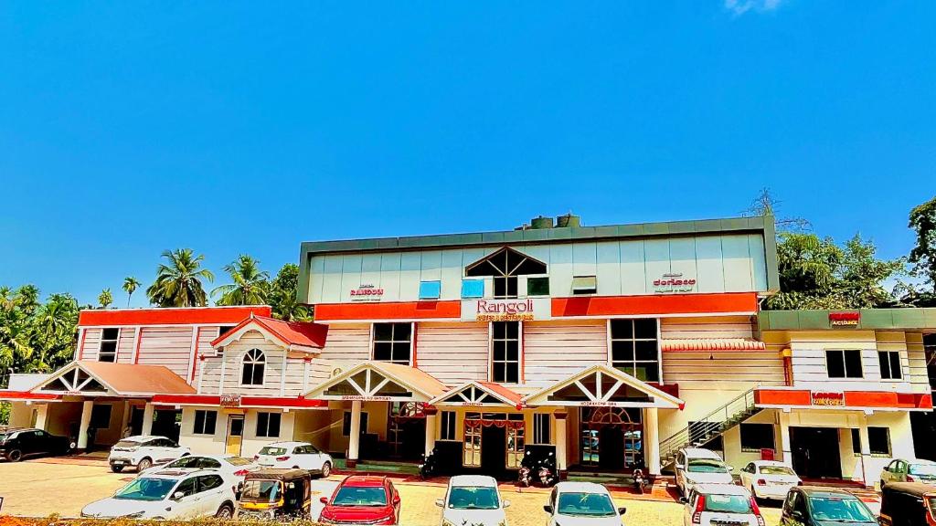 a large building with cars parked in a parking lot at Rangoli Suites & Restrobar in Bantvāl