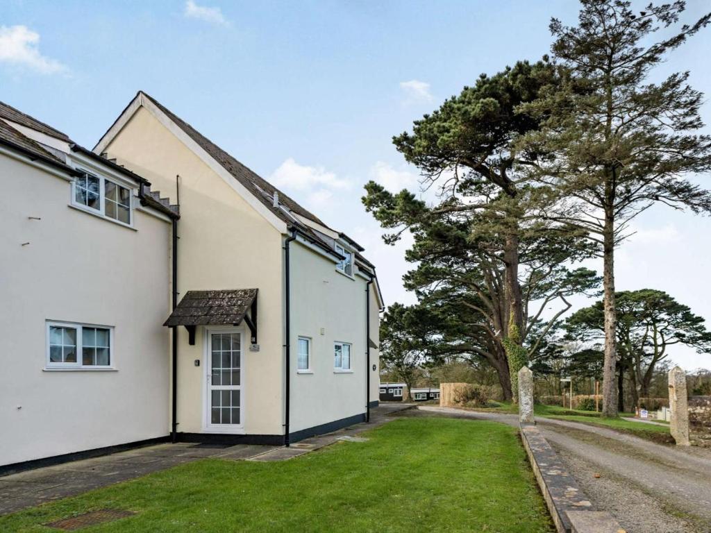 an exterior view of a white house with a tree at 2 Bed in Bude oc-86920 in Kilkhampton