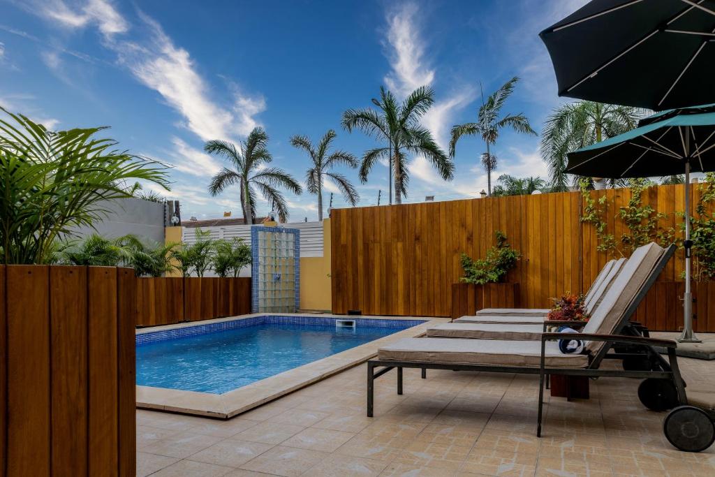 a swimming pool with chairs and an umbrella at Kululwa House in Luanda