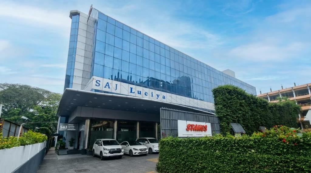 a building with cars parked in a parking lot at Hotel Saj Luciya in Trivandrum