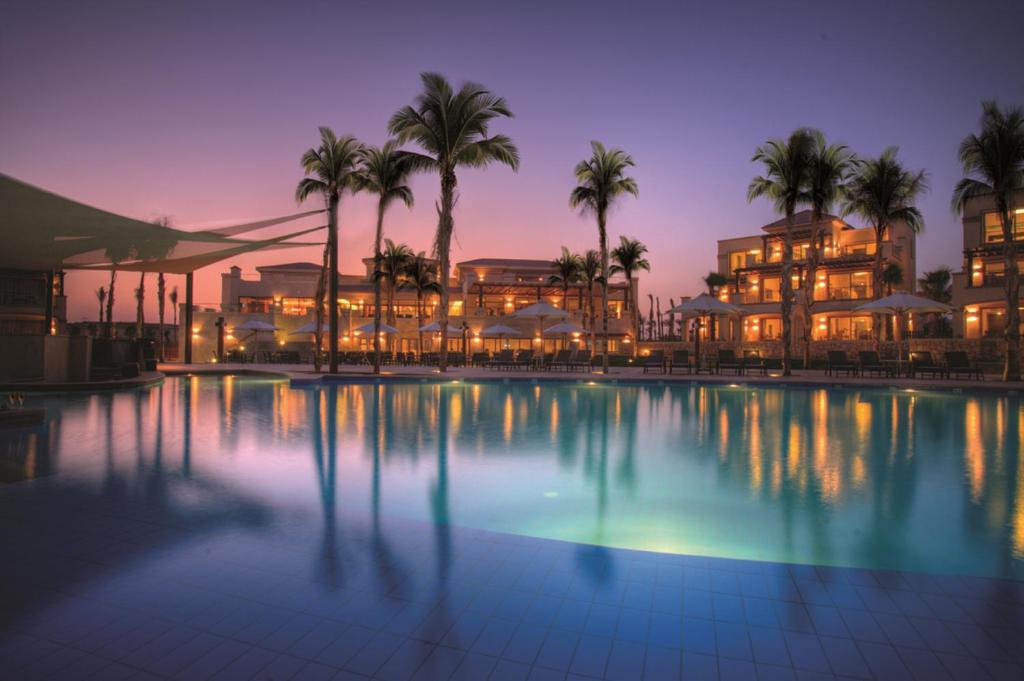una piscina de hotel con palmeras y un edificio en Jaz Little Venice Golf Resort, en Ain Sokhna