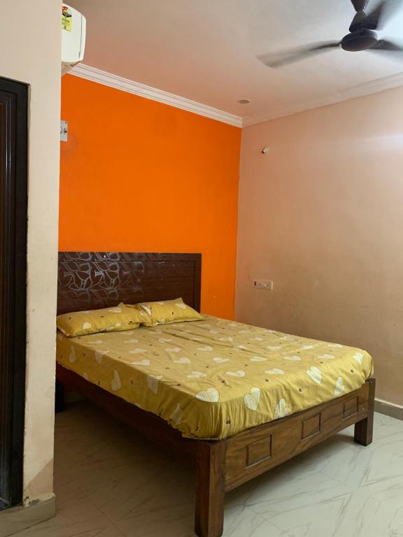 a bed in a room with an orange wall at Amaravathi Convention & Function hall in Penuganchiprolu