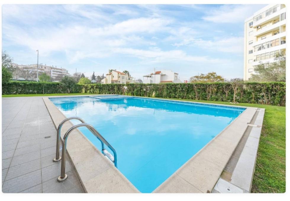 a large swimming pool with blue water at Sunny apartamento in Portimão