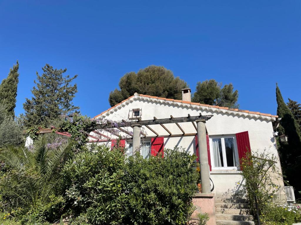 a white house with a red window and trees at La petite maison près de la mer, avec jardin , parking et clim in La Ciotat