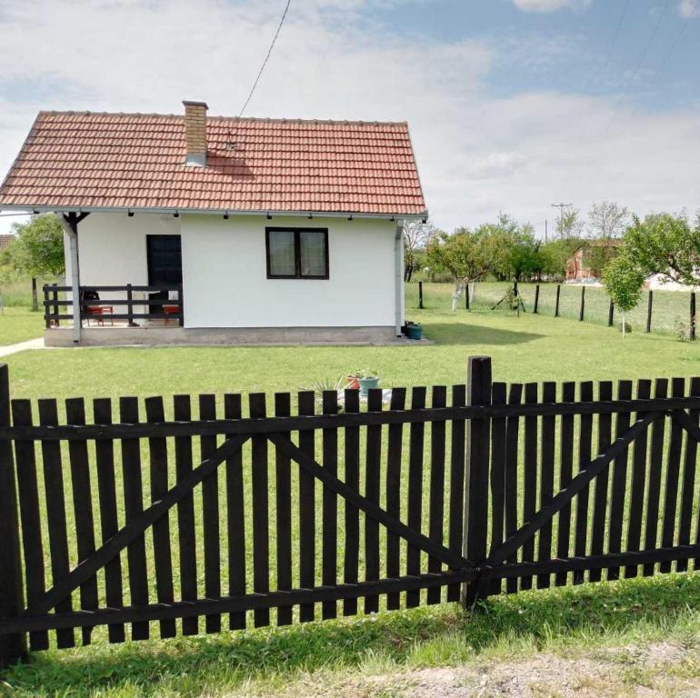 a white house with a red roof behind a fence at Veseli svet-Zvizdar,Ub in Ub