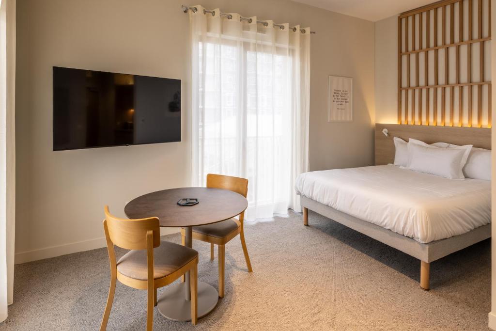 a bedroom with a bed and a table and a bed and a table and chairs at Le PIC in Clermont-Ferrand