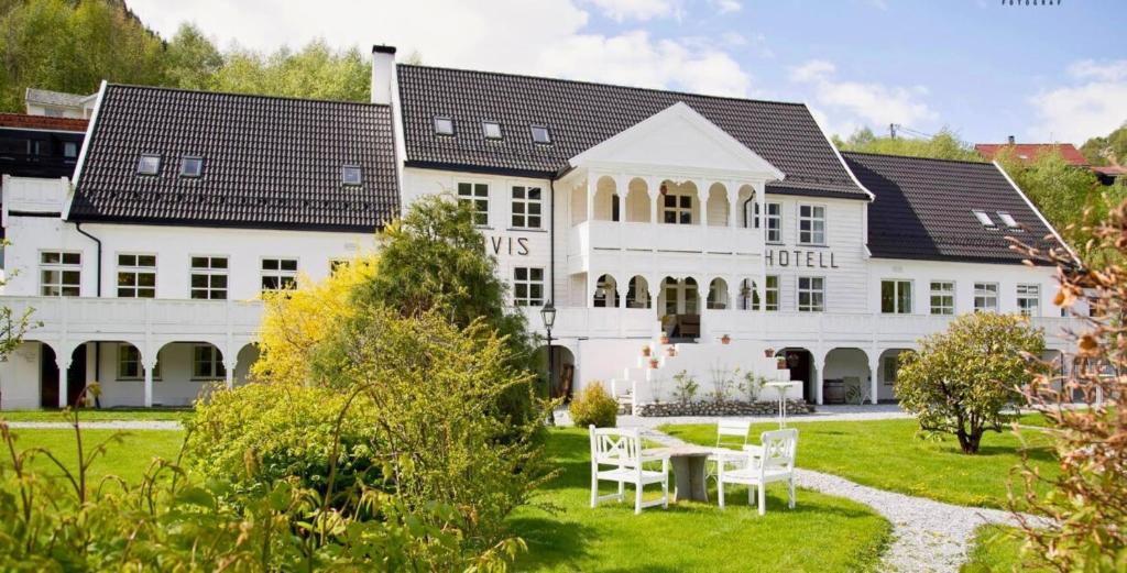 a large white building with a table in front of it at Tørvis Hotell in Luster