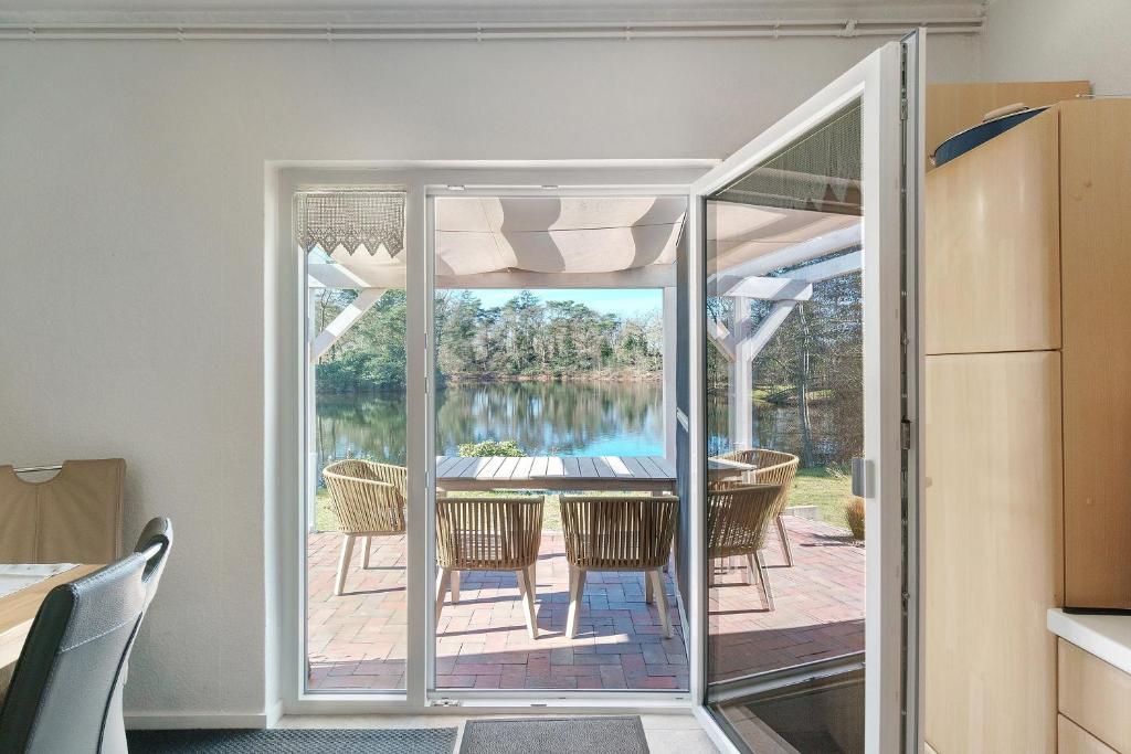 a room with a glass door leading to a table and chairs at Idyllic Lakeside Cottage in Bockhorn