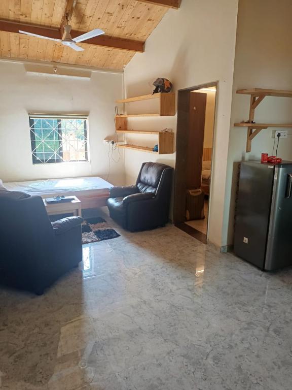 a living room with a couch and a refrigerator at Harmal's Residency in Arambol