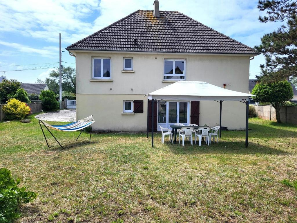 a house with a table and chairs and an umbrella at Maison De Bord De Mer Alizée in Saint-Germain-sur-Ay