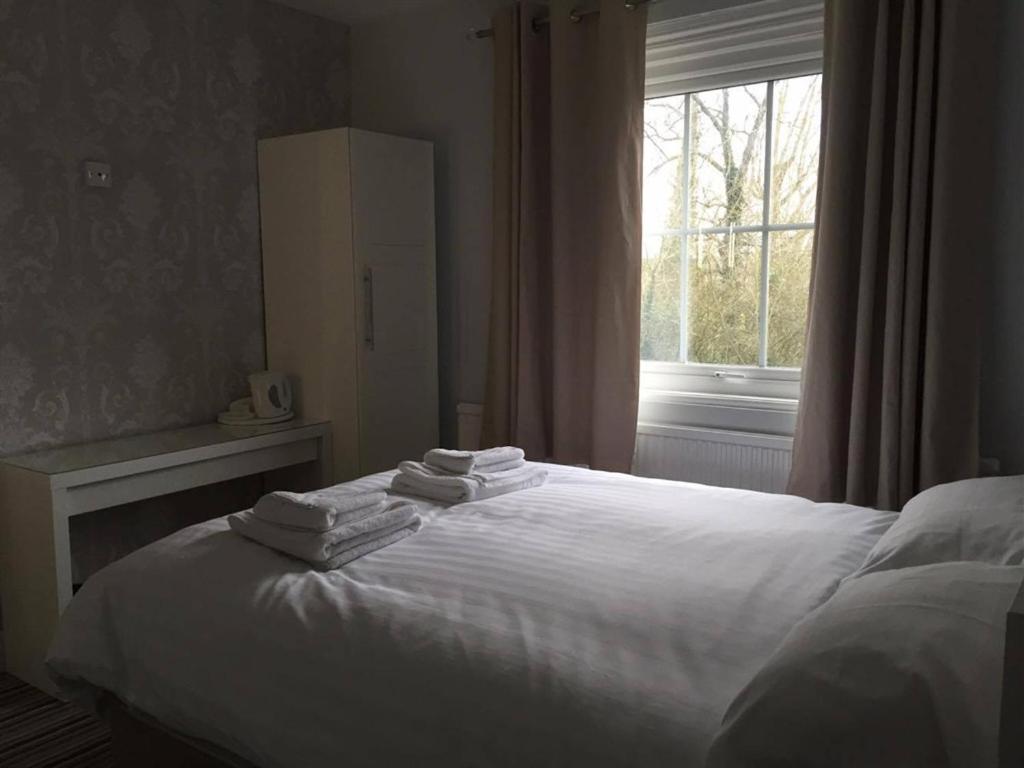 um quarto com uma cama com lençóis brancos e uma janela em The Volunteer Inn em Wantage