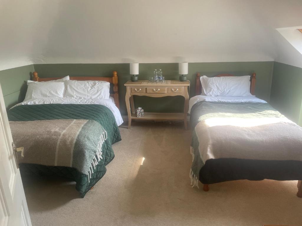 a room with two beds and a side table at Shanboley Cottage in Ballinasloe