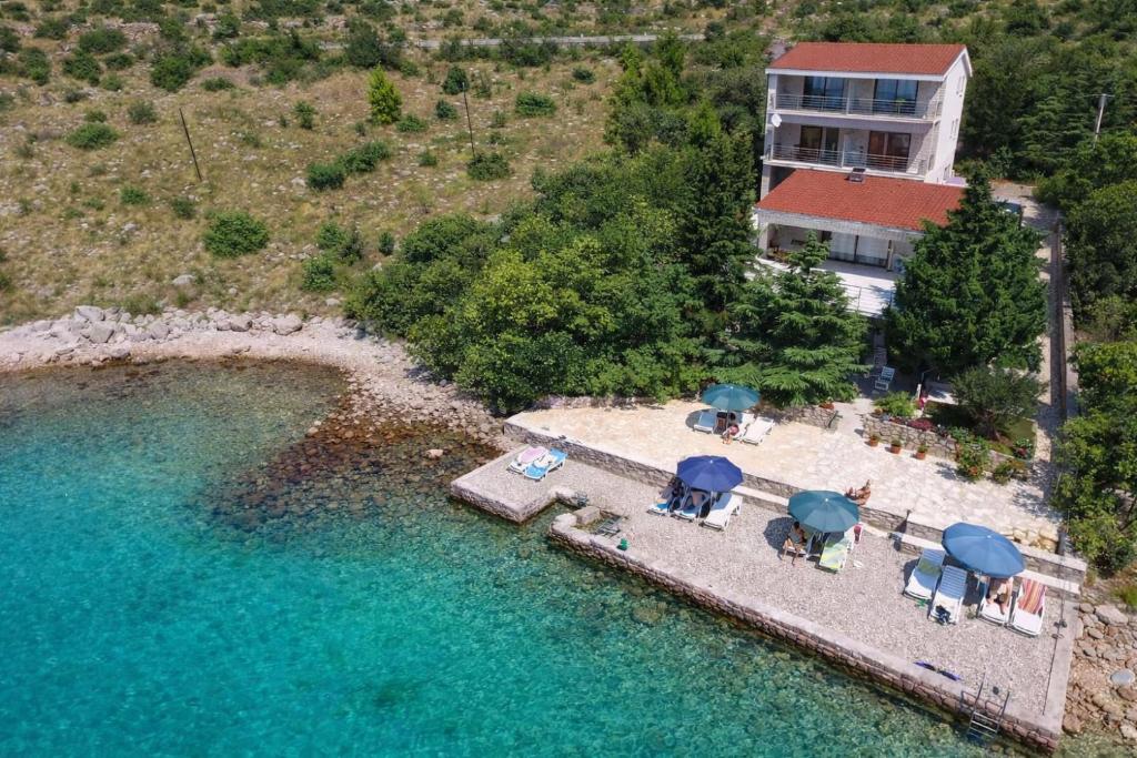 an aerial view of a beach with chairs and umbrellas at Apartmani Ribarica**** in Karlobag