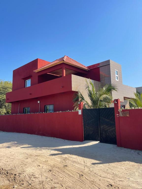 a red house with a red fence in front of it at Auberge Andel Diabou SARR in Palmarin