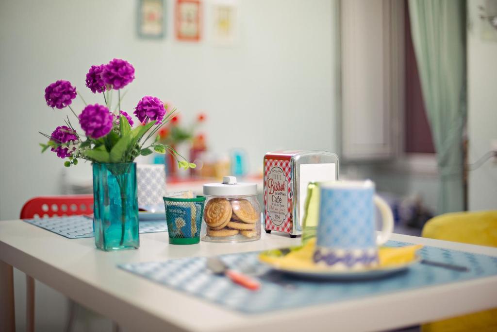 einen Tisch mit einer Vase lila Blumen und Getränken in der Unterkunft Viaggio a Napoli B&B in Neapel