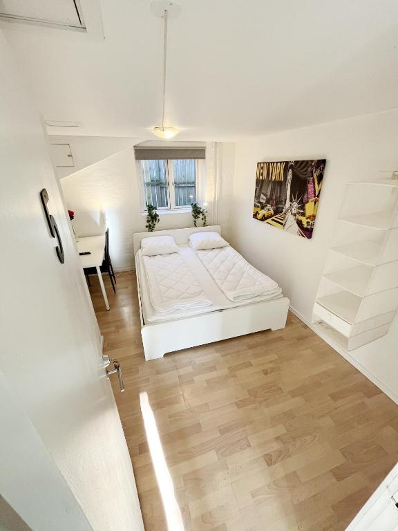 a white bedroom with a bed and a table at Central Large Double Room with free parking in Aalborg