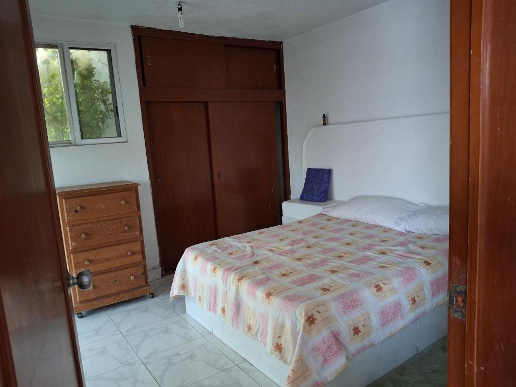 a bedroom with a bed and a dresser and a window at Casa Rosa in Tequesquitengo