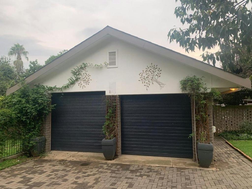 a garage with two garage doors in front of a house at Cloete Self Catering Sky Room in Ermelo