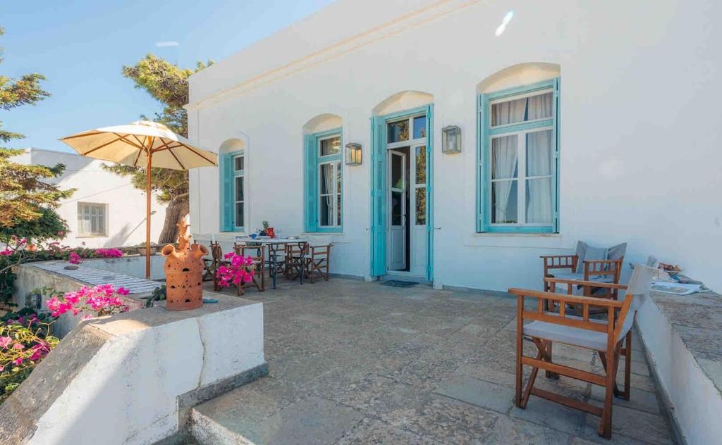 a white house with a patio with chairs and an umbrella at Captain's Mansion Exampela in Apollonia