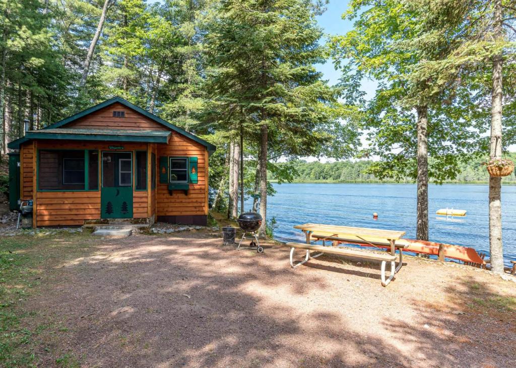 a cabin with a picnic table next to a lake at Bayside - Bouchard Shores Resort in Minocqua