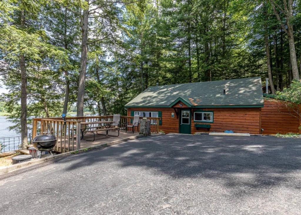 a small wooden cabin with a grill and a table at Timbers - Bouchard Shores Resort in Minocqua
