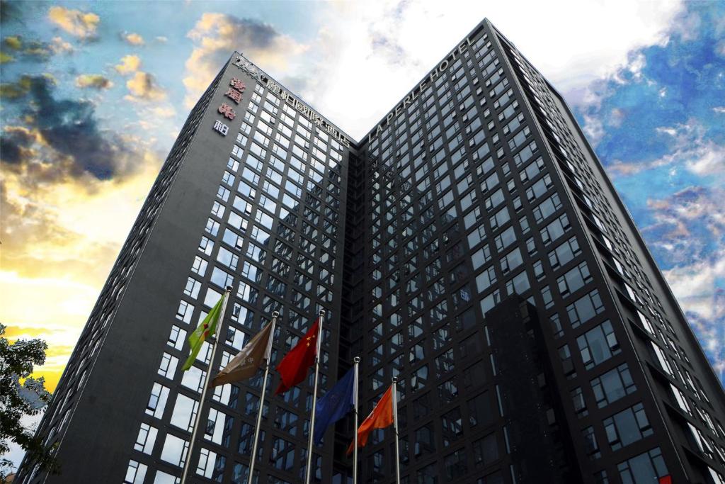 a tall building with flags in front of it at La Perle International Hotel - Free shuttle between hotel and Exhibition Center during Canton Fair & Exhibitor registration Counter in Guangzhou