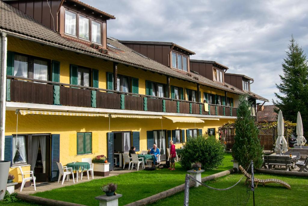 a large yellow building with people sitting outside of it at Ferien- und Reiterhof Ochsenkopf in Missen-Wilhams