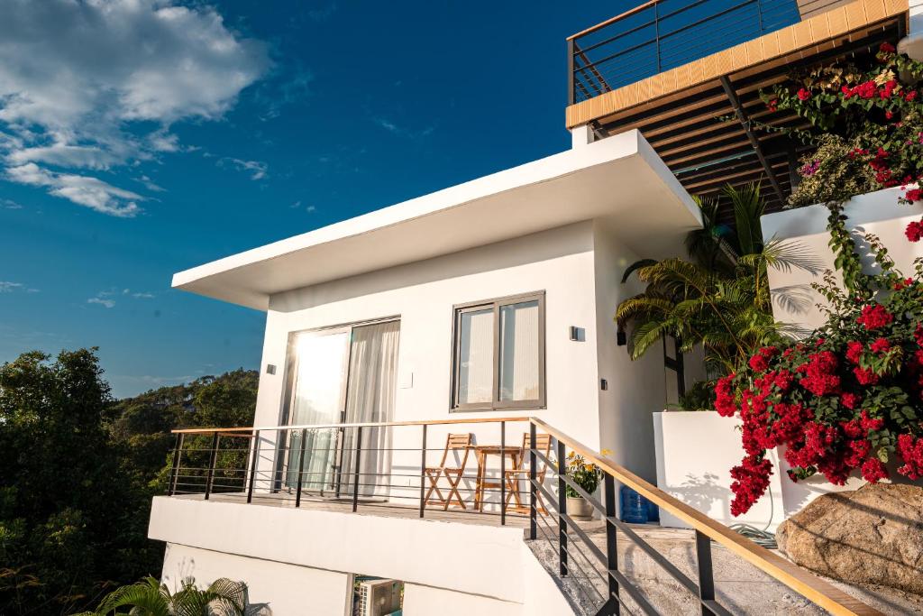 a white house with flowers on the balcony at Titine Apartment in Srithanu