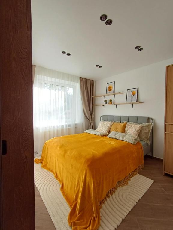 a bedroom with a bed with an orange blanket at Cozy Stay Marijampolė in Marijampolė