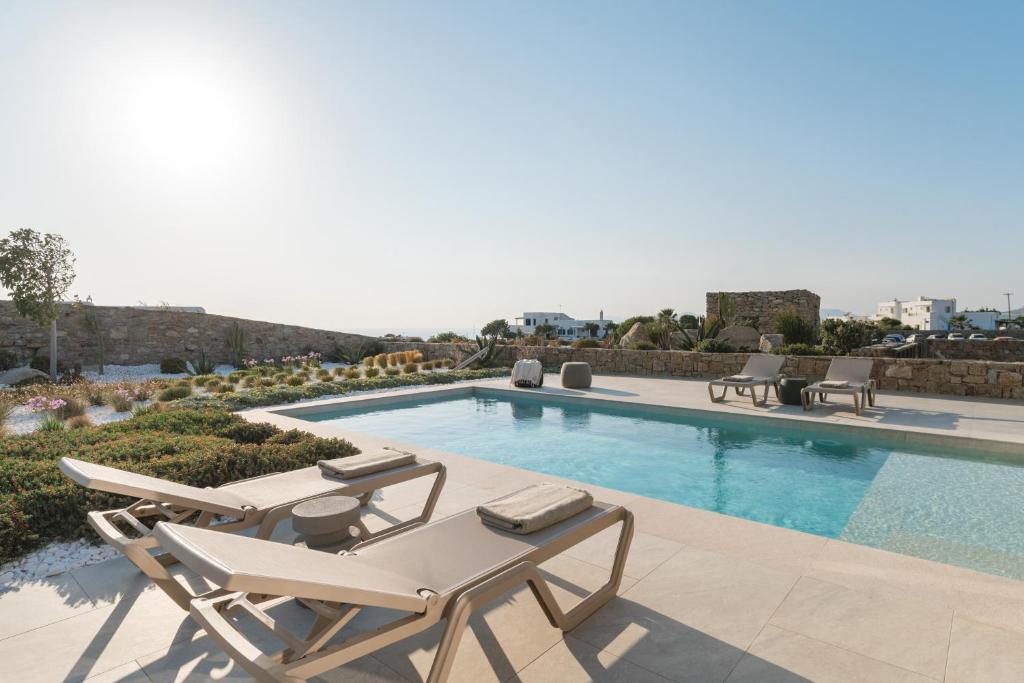 a swimming pool with chaise lounge chairs and a swimming pool at Omvrodektis Village in Mykonos Airport