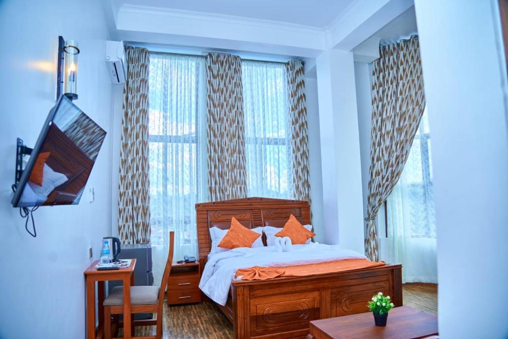 a bedroom with a bed and a desk and window at Sumni Hotel in Nkoanrua