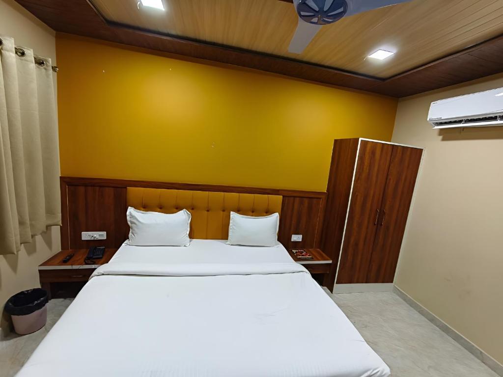 a bedroom with a large bed with a yellow wall at Hotel Ajmer Pride in Ajmer