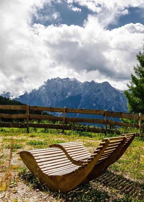 a wooden hammock sitting on the grass in front of a fence at Flasswiesen Alm - ruhige Almhütte in Osttirol in Lienz