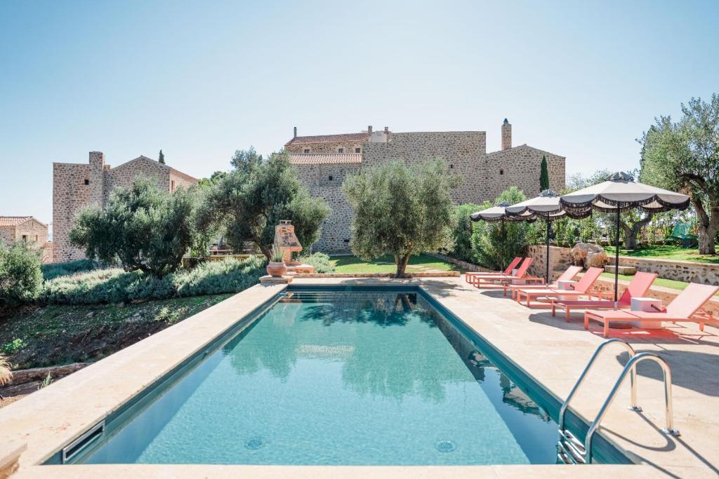 a pool with chairs and umbrellas in front of a building at Alistos Hotel in Gythio