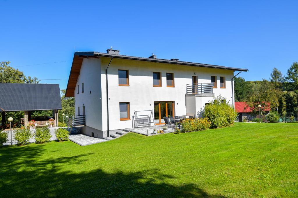 a large white house with a large yard at Apartamenty Tilia Laskowa - Zator in Laskowa