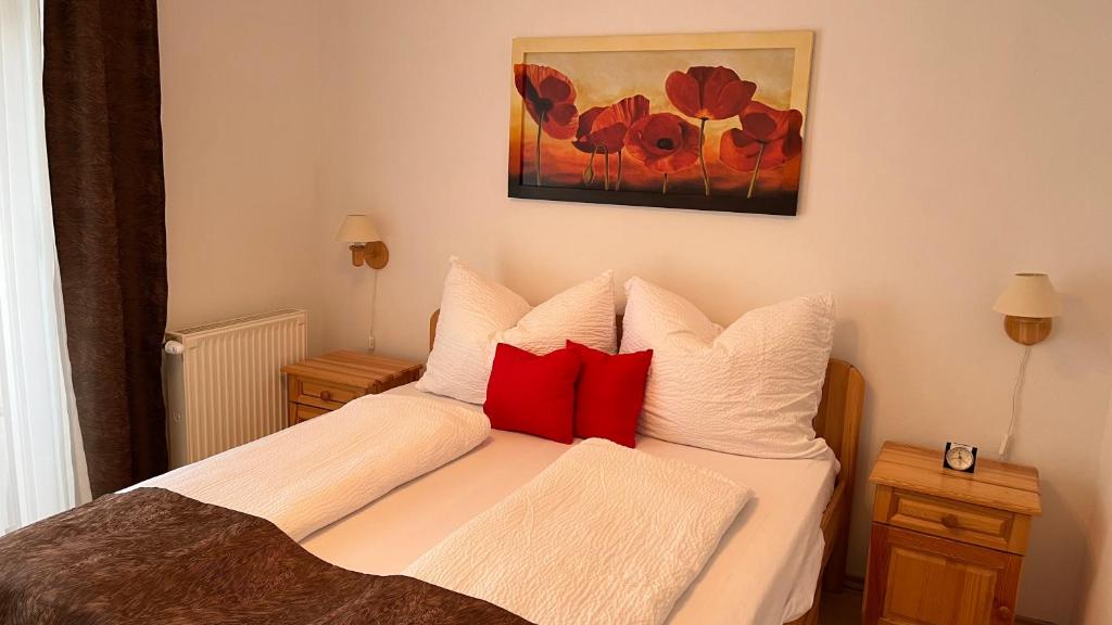 a bedroom with a bed with red pillows and a painting at KŐNIG APARTMAN III. in Hévíz