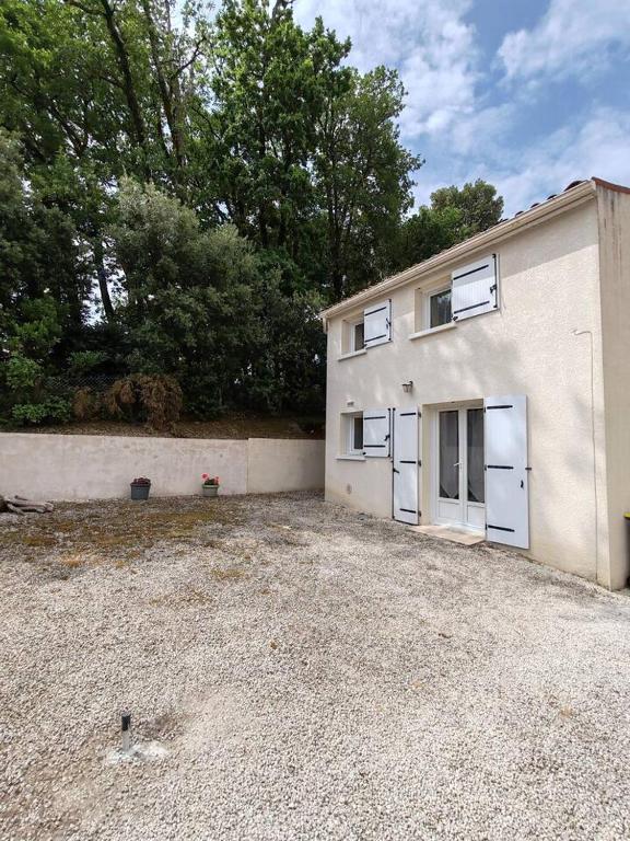 a building with two garage doors in a gravel parking lot at Maison proche plage et commodités in Meschers-sur-Gironde