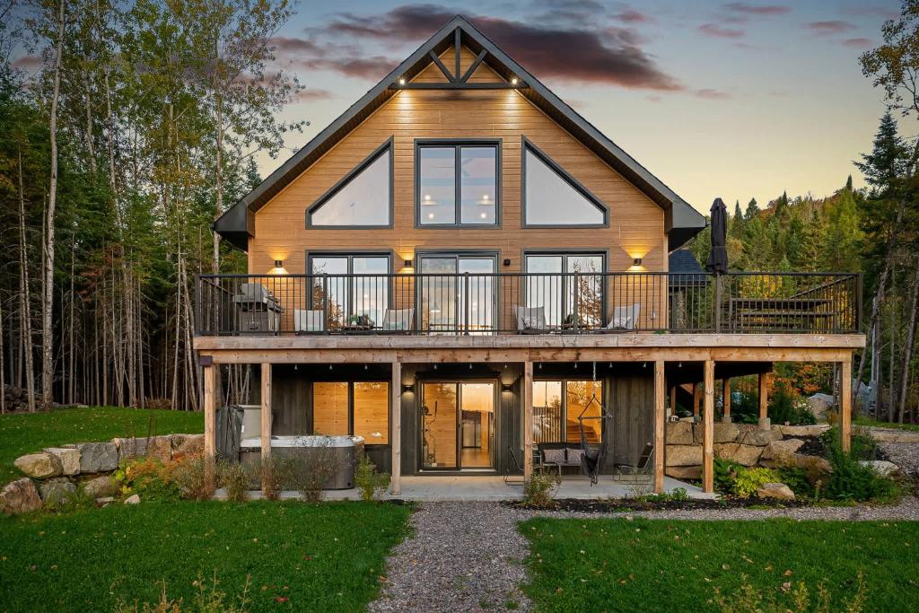 a house with a wrap around porch with a deck at Chalet Le Solem Golf et Spa in Saint-Faustin