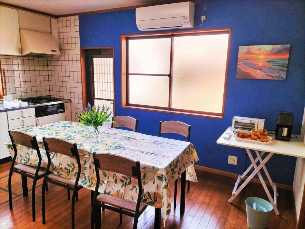a kitchen with a table with chairs and a blue wall at さくらVillaCOAST in Futtsu