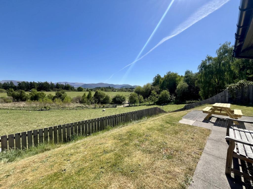 a picnic table in a field with a fence at Calluna Cottage in Aviemore