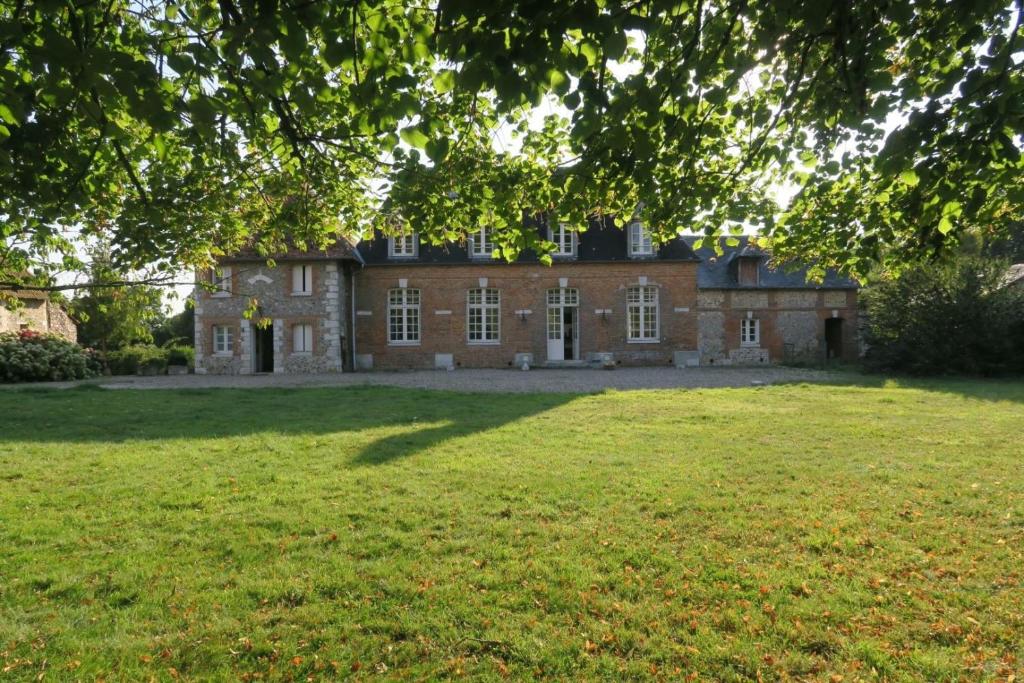 an old brick house with a large lawn in front of it at La Maison de Melmont in Roumare