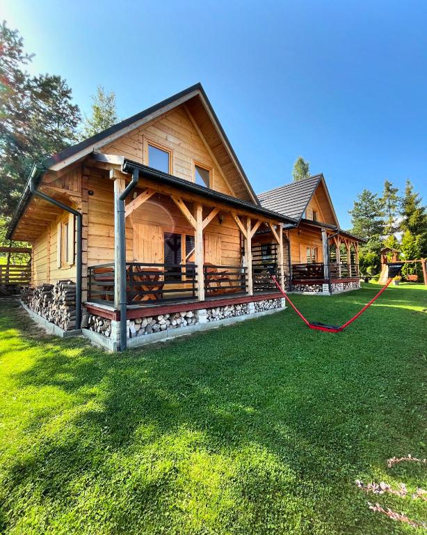 a large log cabin with a red hose at Borowikowe Zacisze drewniane domy z kominkami in Falsztyn